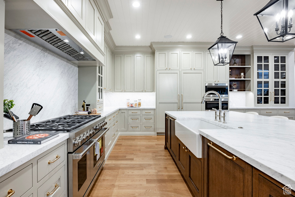 Kitchen featuring custom exhaust hood, a chandelier, stainless steel appliances, light wood-style flooring, and recessed lighting