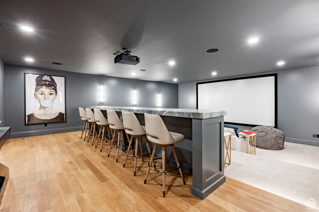 Home theater room with bar area, light wood-type flooring, and recessed lighting