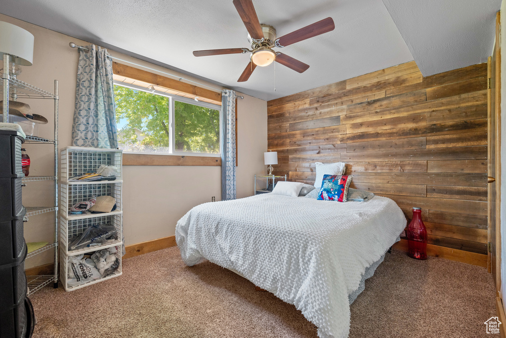 Carpeted bedroom with wood walls, baseboards, and ceiling fan