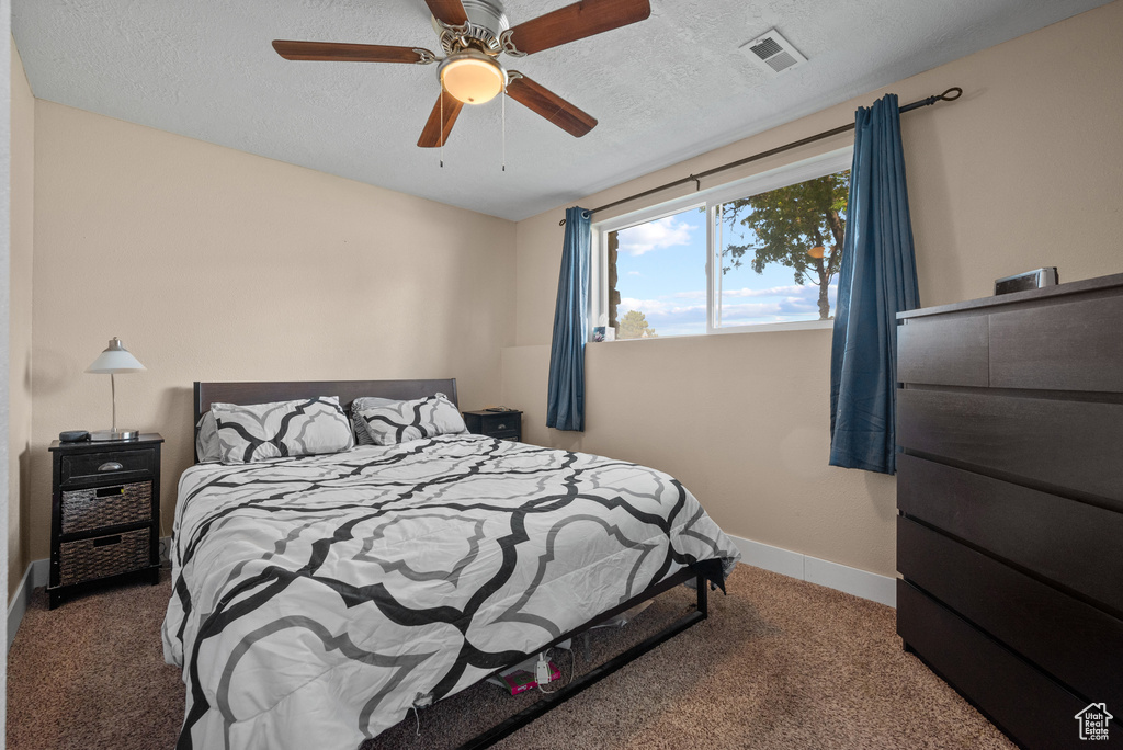 Bedroom with carpet floors, baseboards, ceiling fan, and a textured ceiling