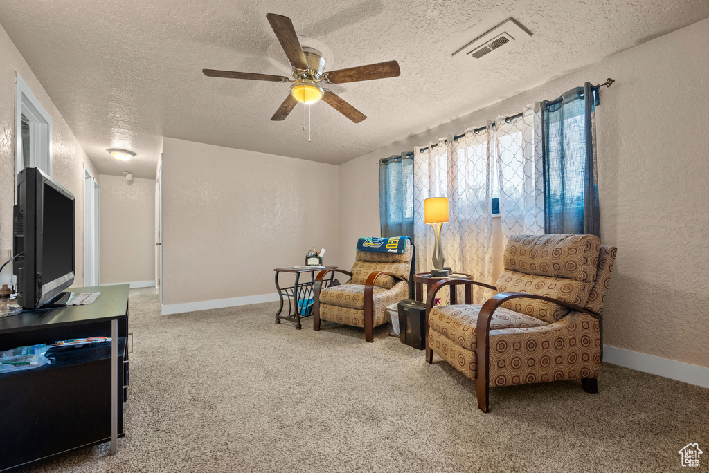Sitting room with a textured ceiling, baseboards, ceiling fan, and carpet