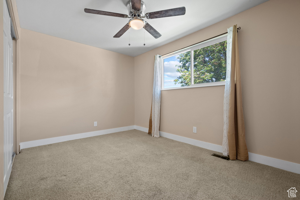 Carpeted empty room featuring ceiling fan and baseboards