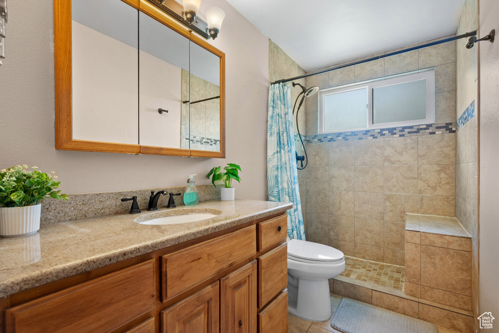 Full bathroom featuring a tile shower, vanity, toilet, and tile patterned flooring