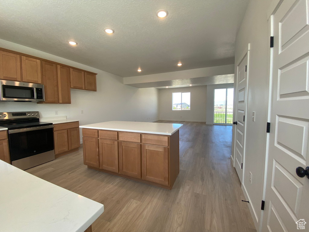 Kitchen featuring appliances with stainless steel finishes, light wood-type flooring, brown cabinets, recessed lighting, and light countertops