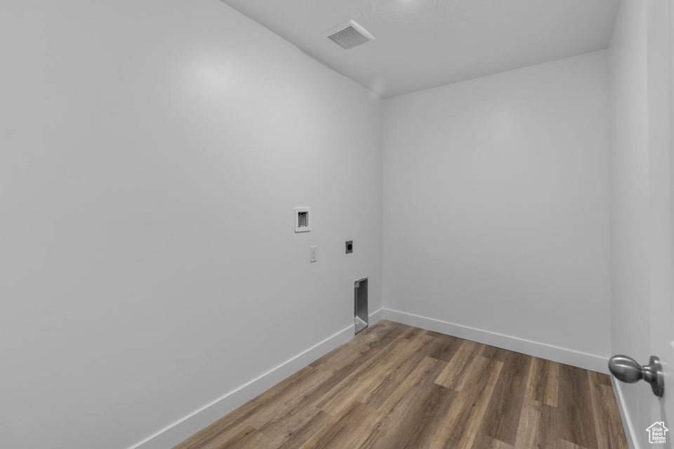 Clothes washing area featuring hookup for an electric dryer, hookup for a washing machine, wood finished floors, and baseboards
