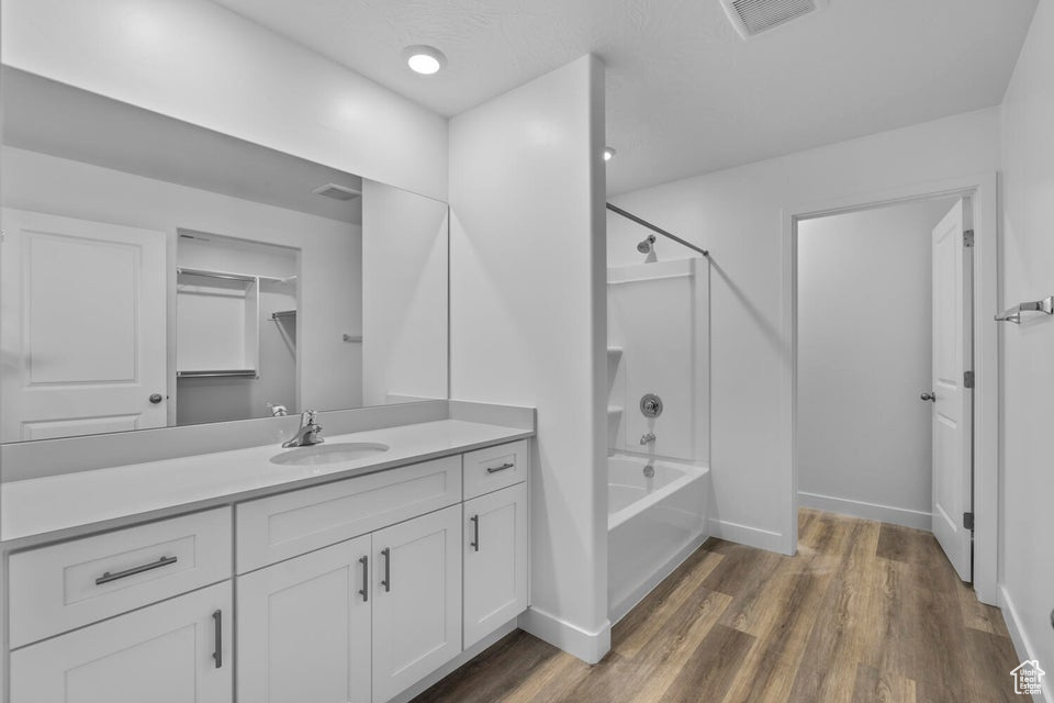 Bathroom featuring vanity, wood finished floors, shower / bath combination, and baseboards