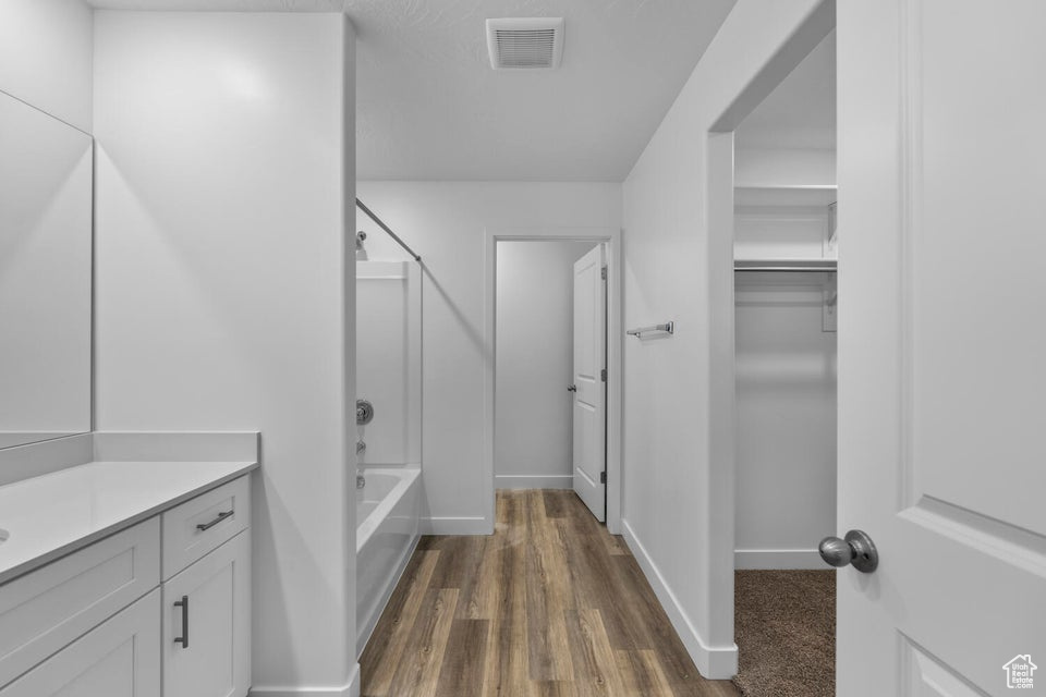 Bathroom featuring vanity, bathing tub / shower combination, wood finished floors, and baseboards