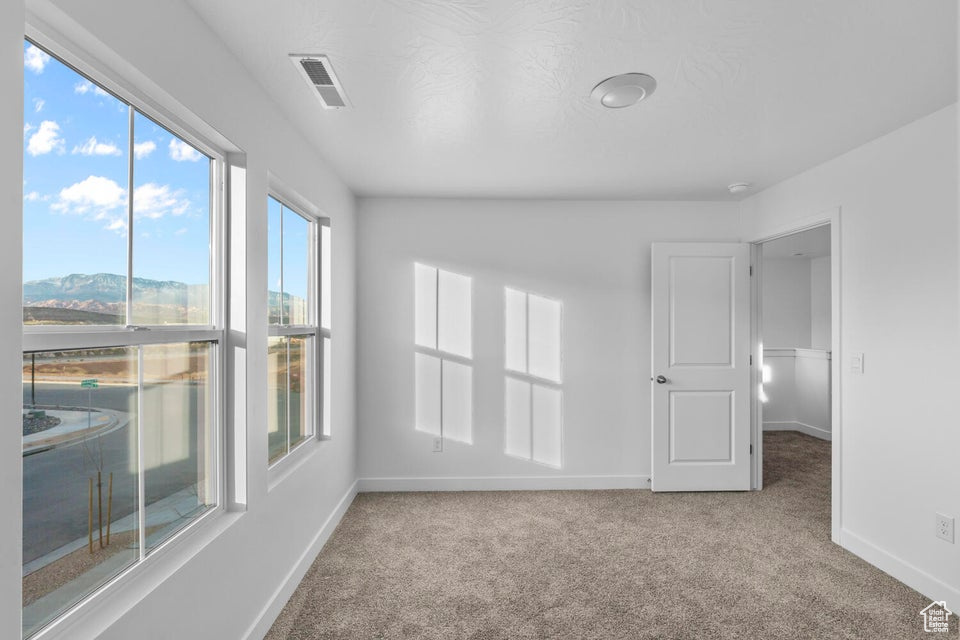 Carpeted spare room featuring baseboards