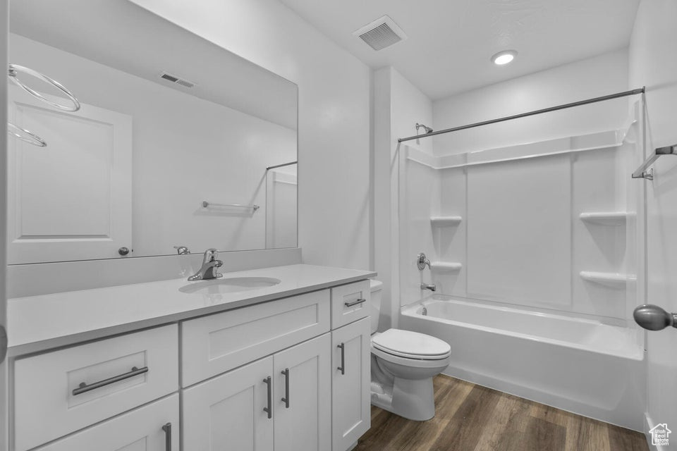 Full bath featuring wood finished floors, toilet, vanity, and shower / bathtub combination