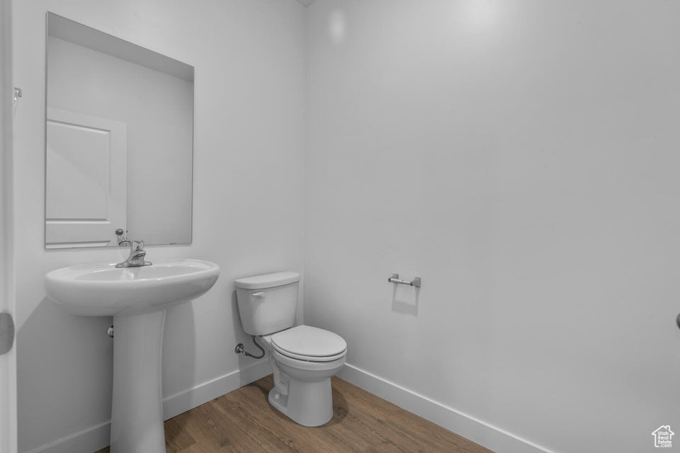Half bath with wood finished floors, baseboards, and toilet