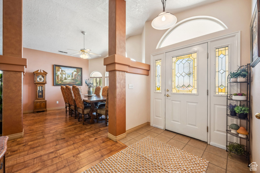 Entrance foyer featuring a ceiling fan, baseboards, healthy amount of natural light, a textured ceiling, and light tile patterned flooring