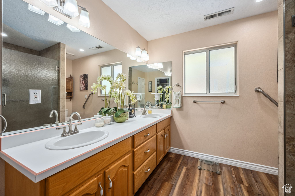 Bathroom with baseboards, wood finished floors, a stall shower, and double vanity
