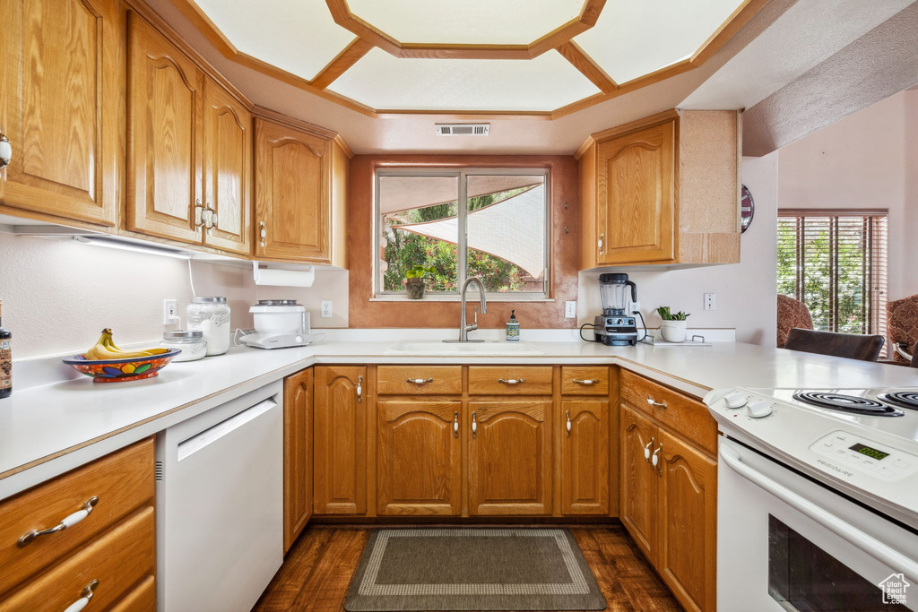Kitchen with white appliances, a sink, light countertops, and dark wood-type flooring