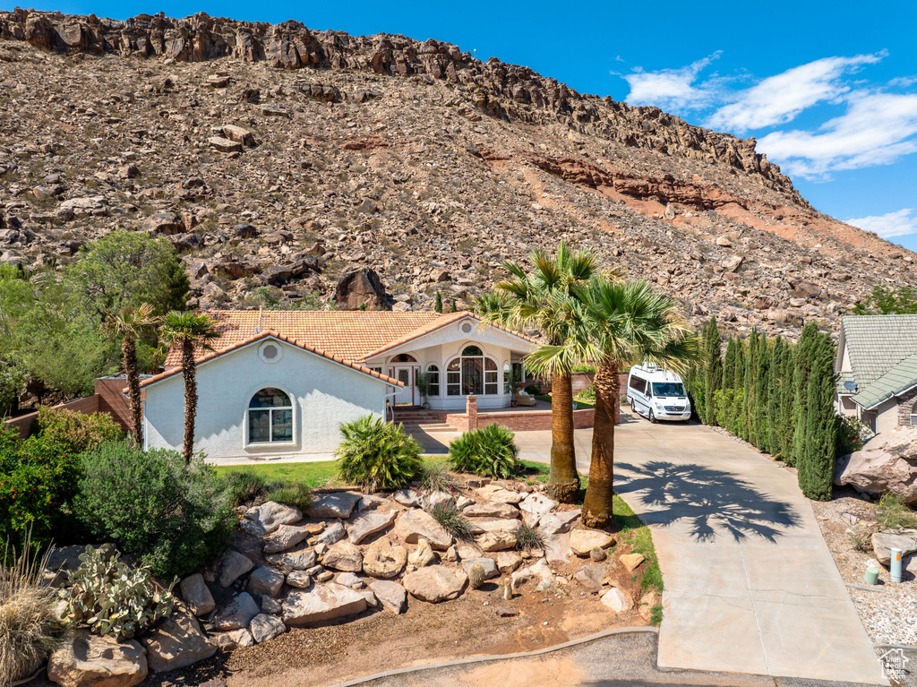 View of front of home with driveway, stucco siding, and a mountain view