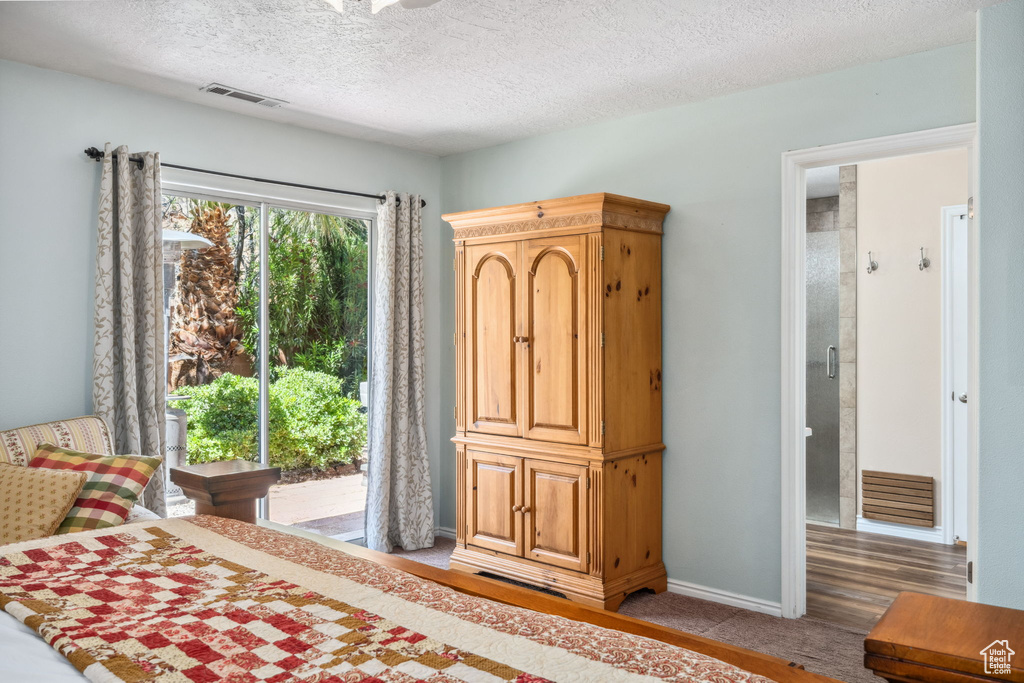 Bedroom featuring a textured ceiling, baseboards, light colored carpet, and access to outside