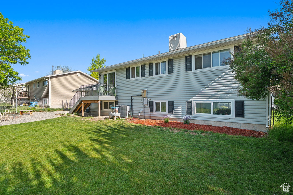 Rear view of house with stairs, a wooden deck, central AC unit, and a chimney