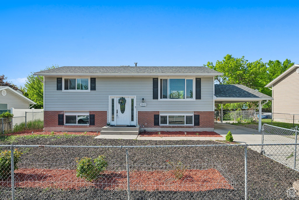 Split foyer home featuring driveway, brick siding, and a carport