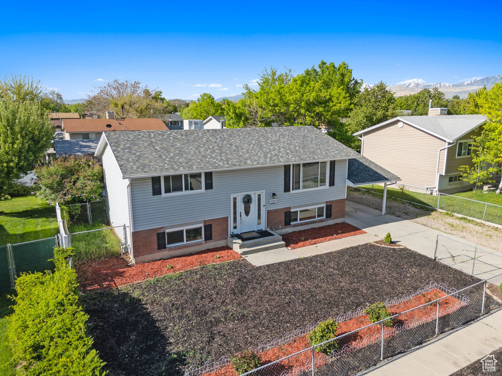 Split foyer home with a carport, brick siding, a shingled roof, driveway, and a fenced backyard