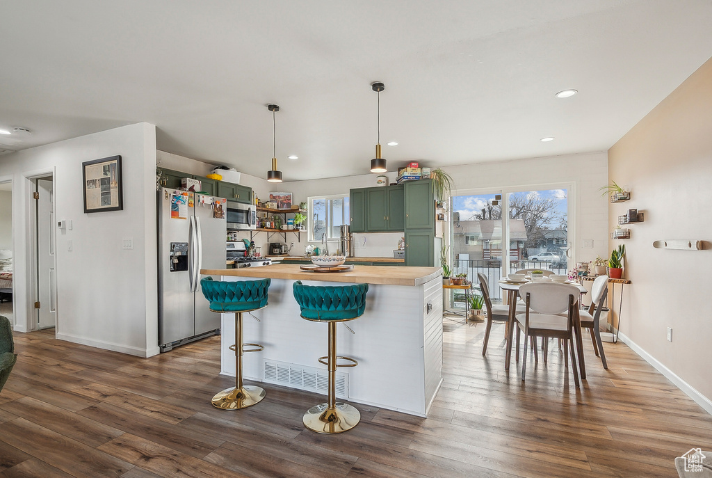 Kitchen featuring green cabinetry, wood counters, appliances with stainless steel finishes, open shelves, and dark wood-style floors