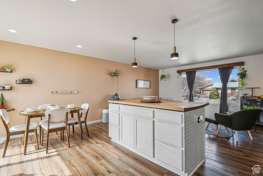 Kitchen with light wood-style floors, white cabinetry, wooden counters, hanging light fixtures, and recessed lighting