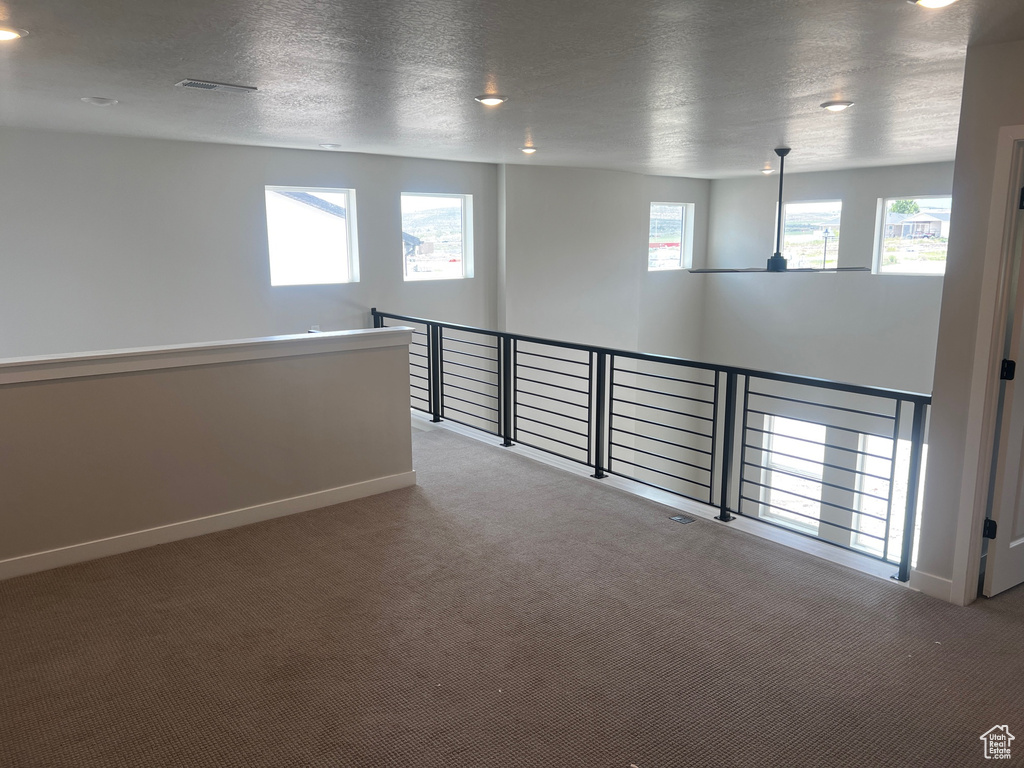 Carpeted empty room featuring baseboards and a textured ceiling