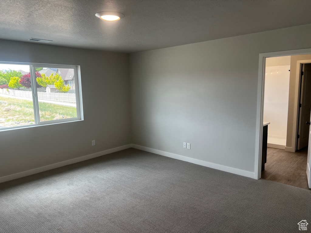 Spare room featuring dark carpet and baseboards