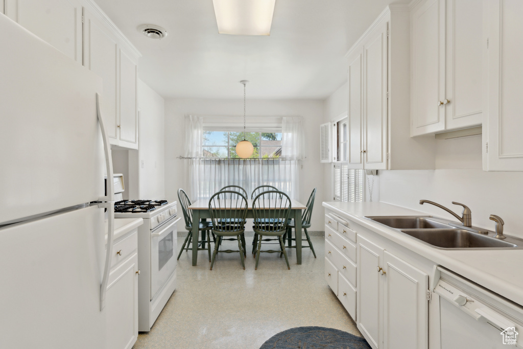 Kitchen featuring white appliances, a sink, white cabinets, and light countertops