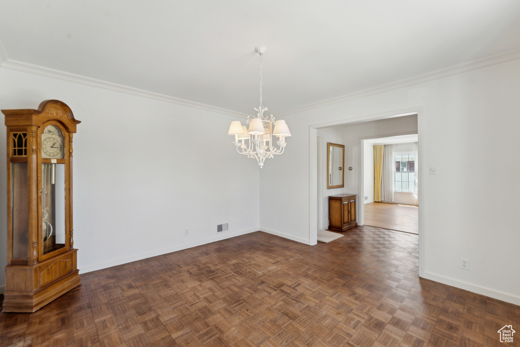 Unfurnished dining area featuring a chandelier, baseboards, and crown molding