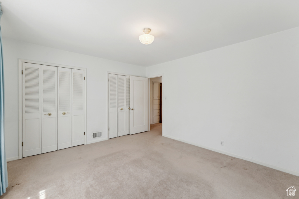 Unfurnished bedroom with multiple closets, carpet flooring, and baseboards