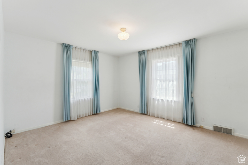 Empty room with healthy amount of natural light, carpet floors, and baseboards