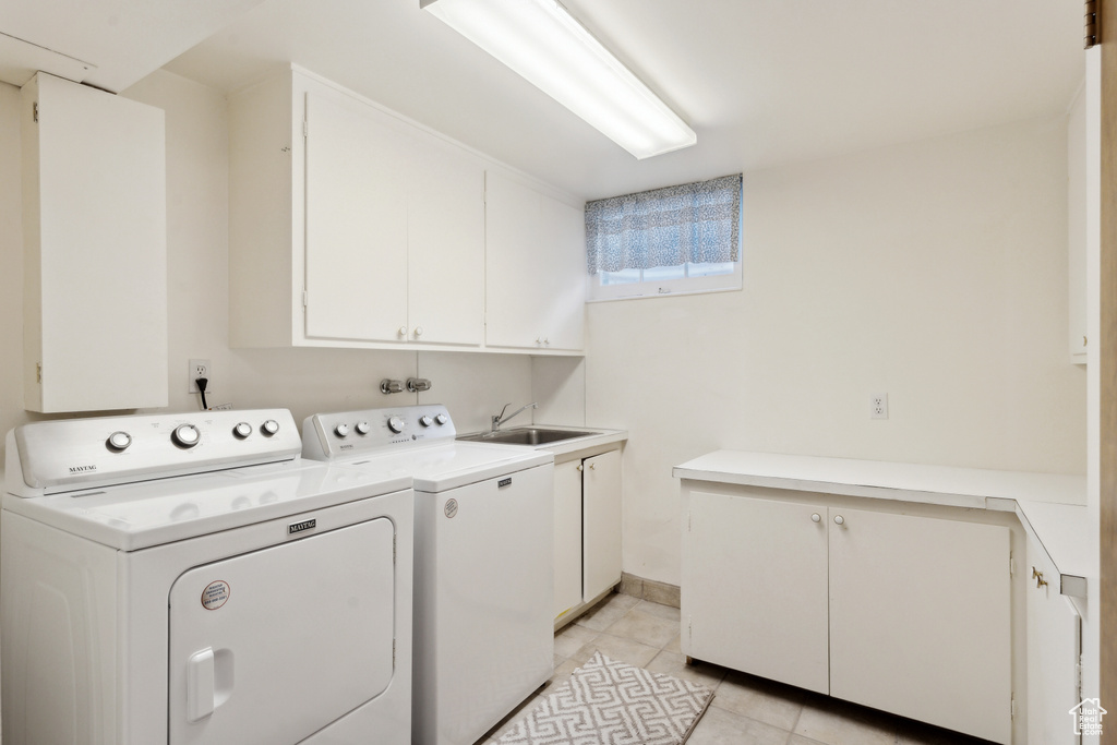 Laundry room with cabinet space, independent washer and dryer, and light tile patterned flooring