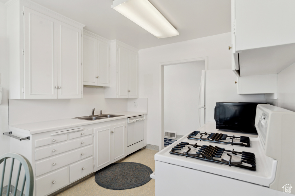 Kitchen featuring white appliances, a sink, white cabinetry, and light countertops