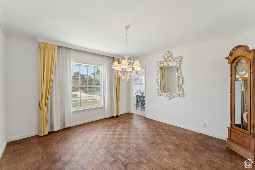 Unfurnished dining area featuring a chandelier, baseboards, and crown molding