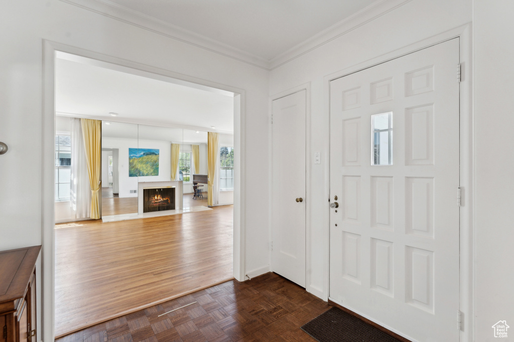 Foyer featuring ornamental molding and a warm lit fireplace