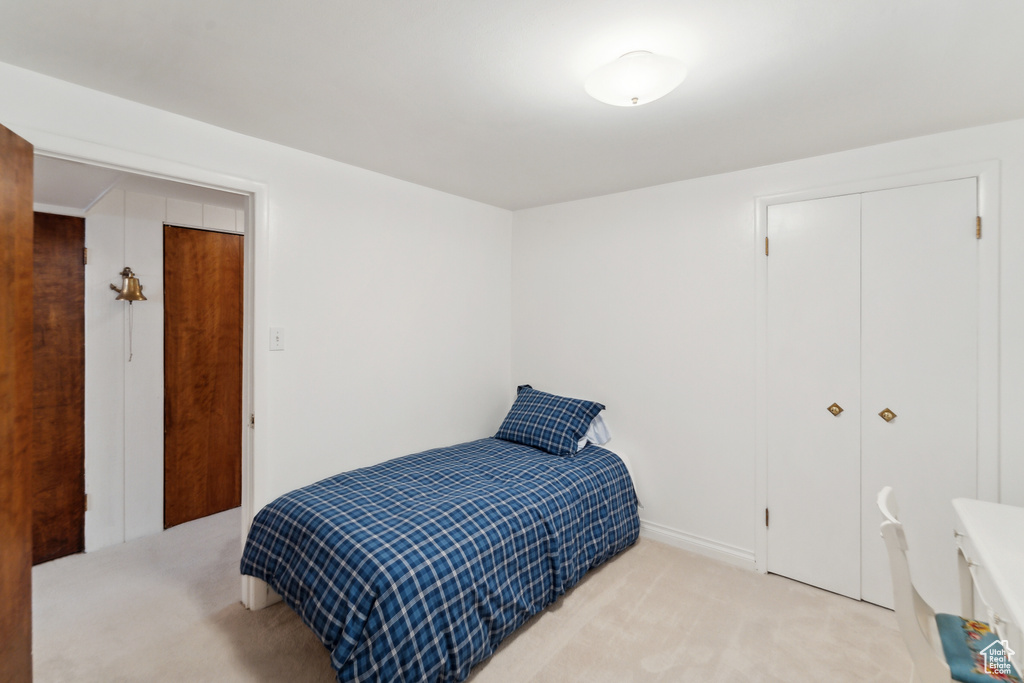 Bedroom with light colored carpet and a closet