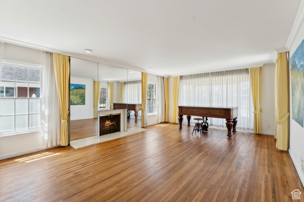 Living area featuring wood finished floors, a warm lit fireplace, crown molding, and baseboards
