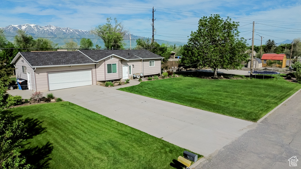 Ranch-style home featuring a front yard, driveway, an attached garage, and a mountain view