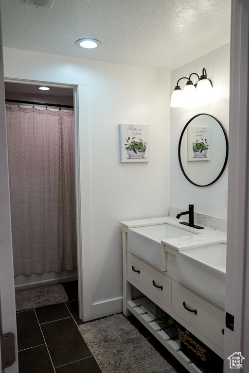 Bathroom with vanity, a textured ceiling, baseboards, recessed lighting, and tile patterned flooring