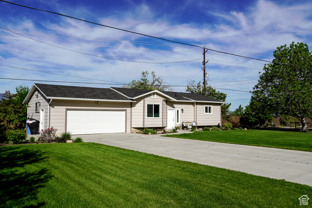 Ranch-style house featuring driveway, a garage, a front lawn, and roof with shingles