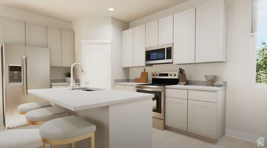 Kitchen with white microwave, fridge with ice dispenser, electric stove, a sink, and a kitchen island with sink
