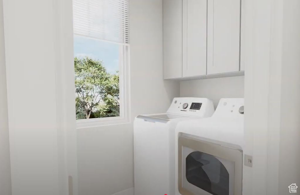 Washroom featuring separate washer and dryer, cabinet space, and plenty of natural light