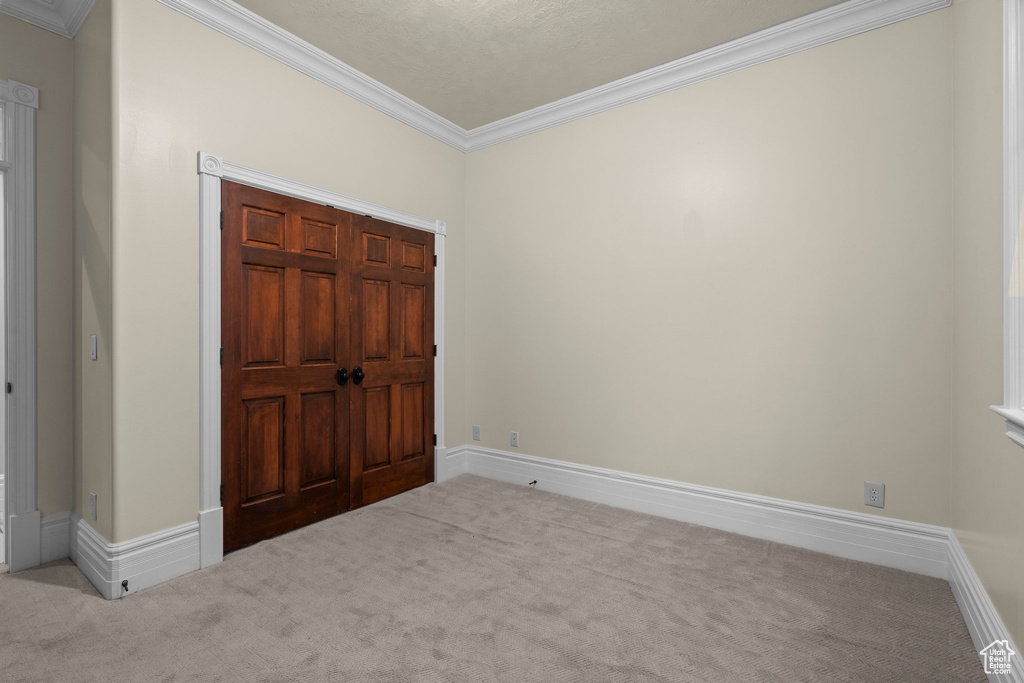 Unfurnished bedroom featuring carpet, ornamental molding, and baseboards