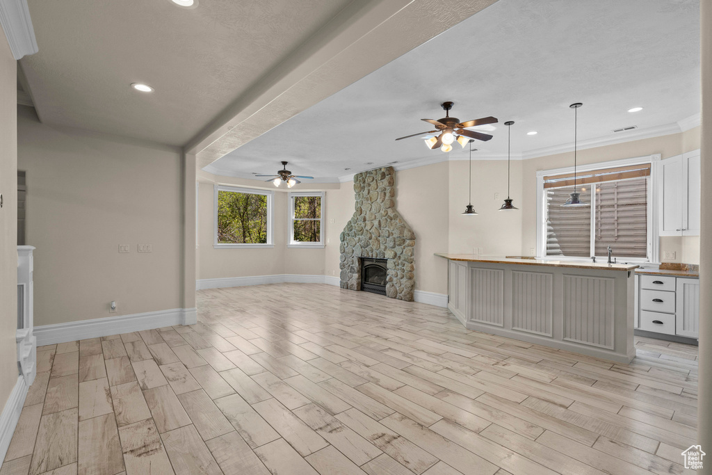 Unfurnished living room featuring ceiling fan, recessed lighting, wood tiled floors, crown molding, and baseboards