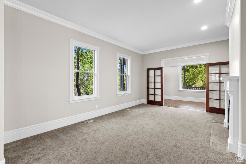 Empty room with carpet flooring, crown molding, plenty of natural light, baseboards, and recessed lighting