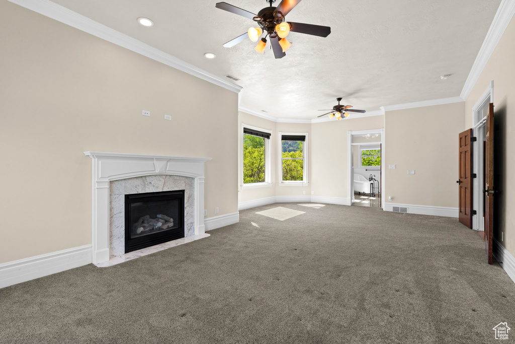 Unfurnished living room with ceiling fan, a high end fireplace, carpet floors, baseboards, and ornamental molding