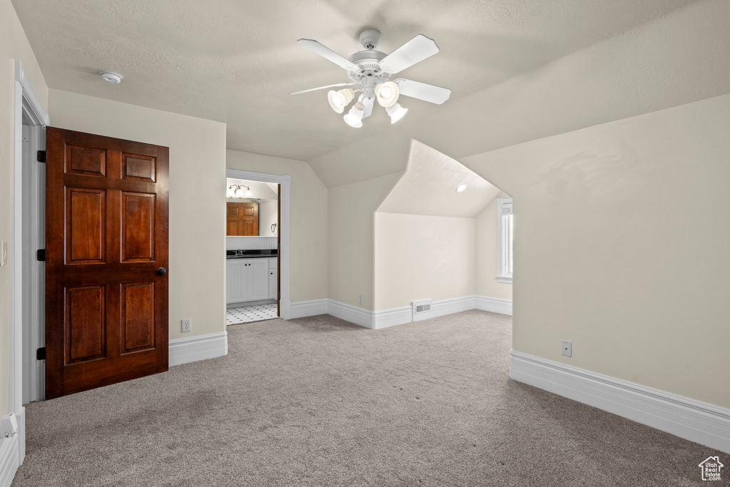 Bonus room featuring carpet floors, a ceiling fan, vaulted ceiling, and baseboards