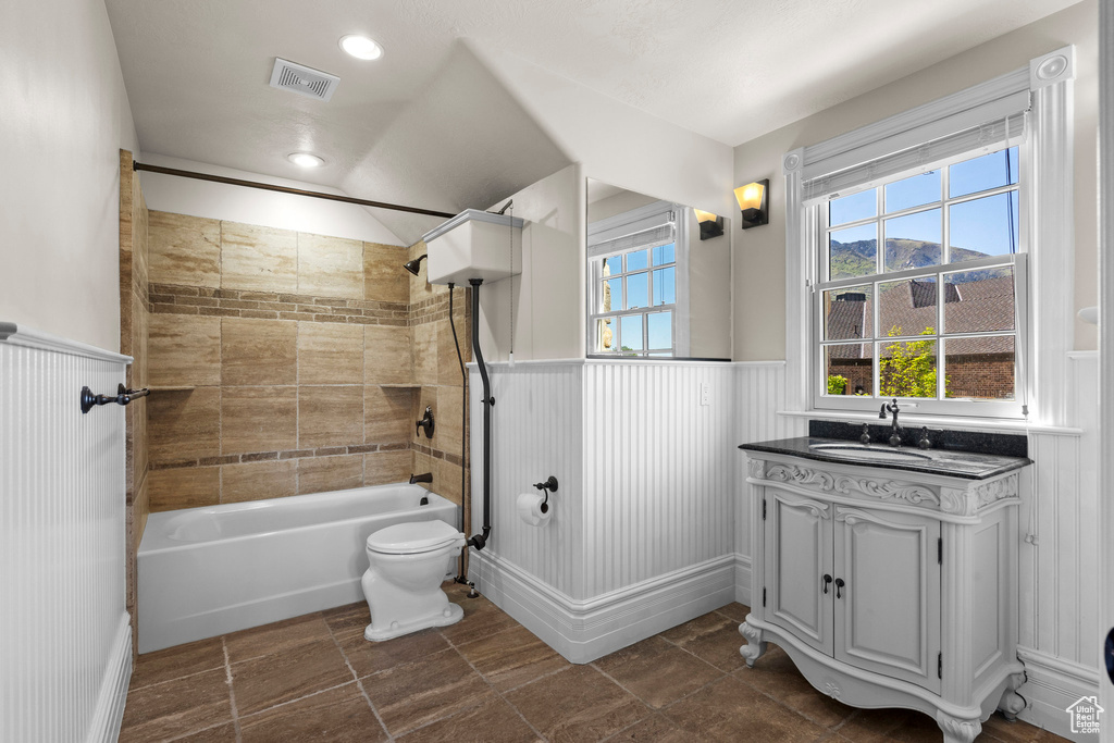 Bathroom with a wainscoted wall, vanity, shower / bath combination, and toilet