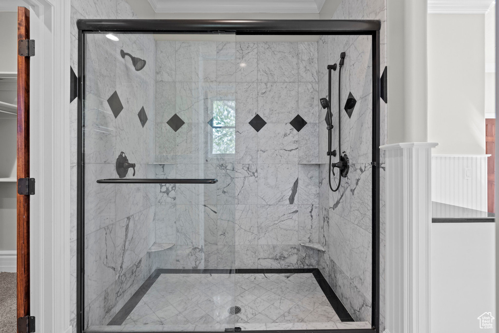 Bathroom featuring ornamental molding and a shower stall