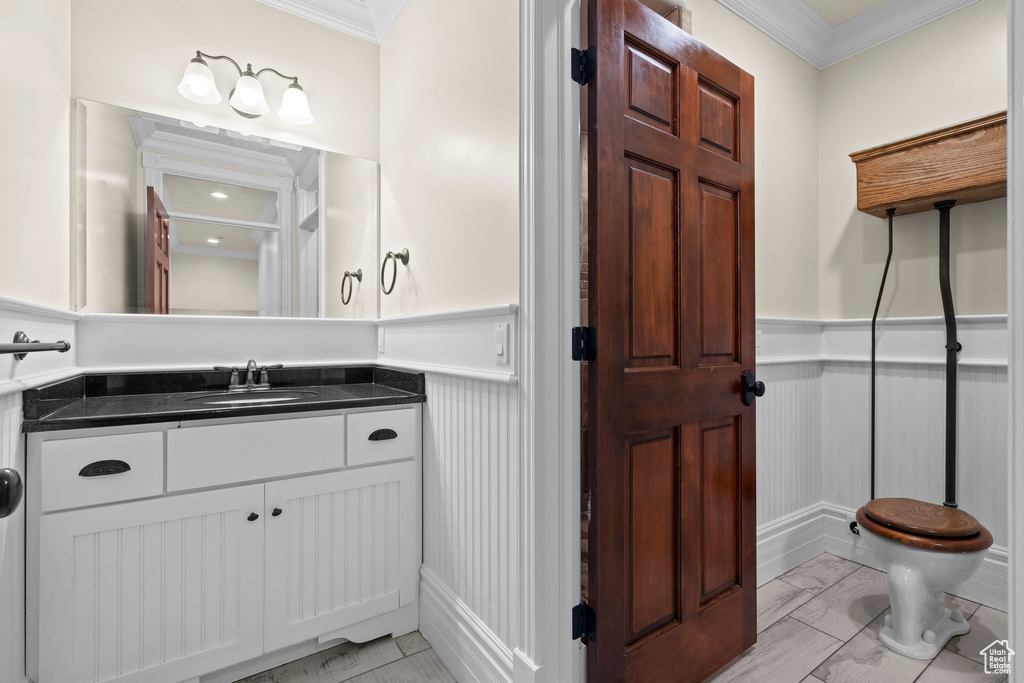 Bathroom with ornamental molding, wainscoting, a decorative wall, vanity, and marble finish floors