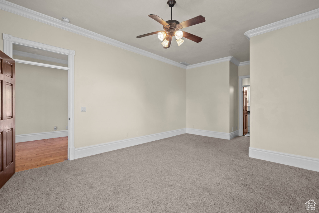 Unfurnished room featuring light carpet, a ceiling fan, crown molding, and baseboards